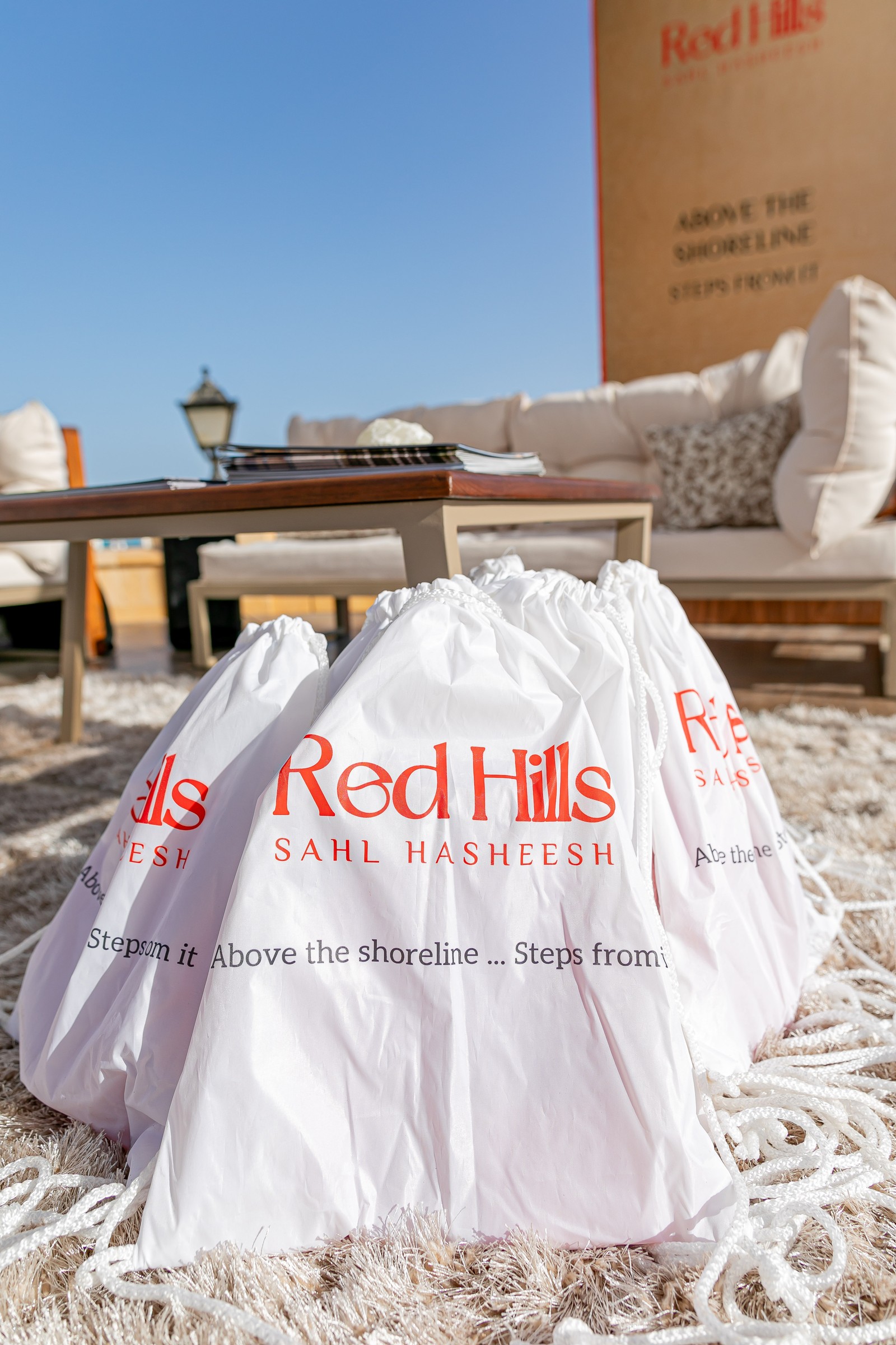 White drawstring giveaway bags carrying the Red Hills Sahl Hasheesh logo